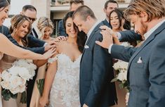 a group of people standing next to each other in front of a bride and groom