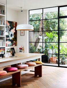 a room with lots of bookshelves and various items on the table in front of large windows