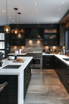 a modern kitchen with black cabinets and white counter tops is lit by pendant lights hanging from the ceiling