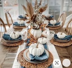 a dining room table set with white pumpkins and blue napkins