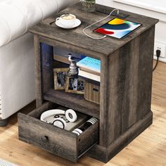 a wooden table with an open drawer on top and some electronics in the bottom compartment