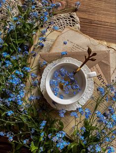 blue flowers in a white cup and saucer on top of an old letter with envelopes