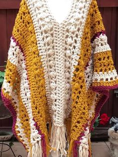 a white and yellow crocheted shawl with tassels