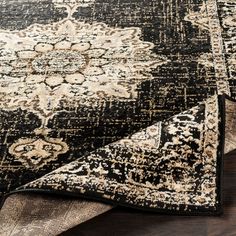 a black and beige area rug on top of a wooden floor