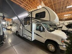 a man standing next to an rv parked in a garage with other recreational vehicles behind him