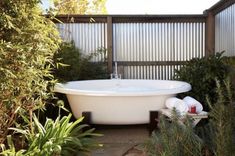 an outdoor bathtub surrounded by plants and shrubs