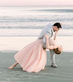 a man and woman are dancing on the beach