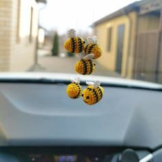 three yellow and black bees hanging from a car dashboard