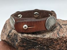 The Buffalo Nickel and Indian Chief Head Concho bracelet features the famous1937 Buffalo Nickel coin. There are 2 Buffalo Nickel Conchos and 3 Indian Head Conchos. The leather is retired horse tack that has been cleaned and conditioned. Button stud closure. Note: Leather will vary based upon what is inventory Introduced in 1913, the Buffalo Nickel was an early hit with collectors and a major circulation workhorse through 1938 when the series ended. Although aficionados prefer the name Buffalo Ni Native American Chief, Hat Holder, American Bison, Cloth Tape, Buffalo Nickel, Indian Chief, Indian Head, Lewis And Clark, The Buffalo