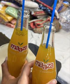 two bottles of orange juice with blue straws