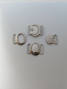 four pieces of metal sitting on top of a white surface with the letters g and l