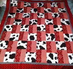 a red and white patchwork quilt with black and white cow prints on the border