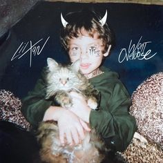 a young boy holding a cat with horns on his head