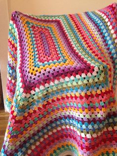 a multicolored crocheted blanket sitting on top of a bed