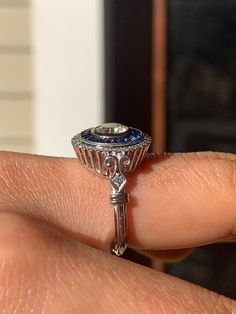 a close up of a person's hand holding a ring with a blue stone