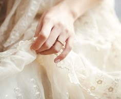 a close up of a person's hand holding a wedding ring on her finger