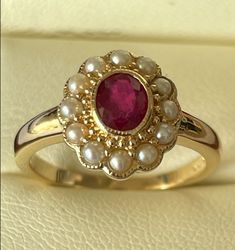 This gorgeous Vintage Inspired Flower Ring has been crafted from 9ct Solid Yellow Gold. A bezel set oval cut NATURAL Ruby with surrounding GENUINE Seed Pearls brings this ring to life. Notice the stamens that surround the petals of this beautiful ring. This is an elegant Victorian inspired ring which simply looks beautiful on a lady who enjoys wearing fine jewellery from a Vintage era. THIS VINTAGE INSPIRED RUBY & PEARL RING IS TRULY AN EXQUISITE FINE JEWELLERY PIECE WHICH IS TO BE TREASURED FOR Ruby Wedding Rings Vintage, Ruby Engagement Ring Art Deco, Victorian Ruby Ring, Vintage Gold Rings Victorian, Vintage Pearl Ring, Gold Ruby Ring, Victorian Ruby Ring Jewelry, Ruby And Pearl Ring, Victorian Gold Ring With Ruby