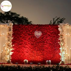 the backdrop is covered with red flowers and lit candles