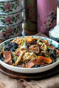 a bowl filled with meat and vegetables on top of a table next to other dishes