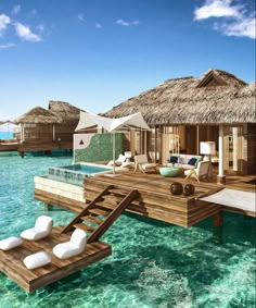 an over water resort with thatched huts on stilts and lounge chairs in the water