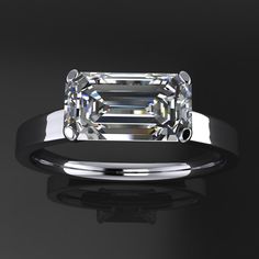 an emerald cut diamond ring on a black background