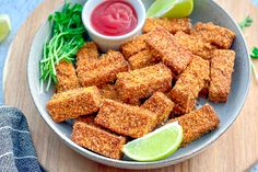 a plate full of fried tofu sticks with ketchup and garnish