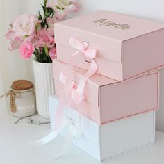 three pink boxes are stacked on top of each other with ribbons and bows around them