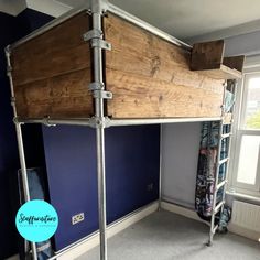 a loft bed made out of metal pipes and wooden planks in a room with blue walls