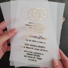 a person holding up some white and gold wedding cards