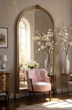 a mirror sitting on top of a wooden floor next to a chair and vase with flowers