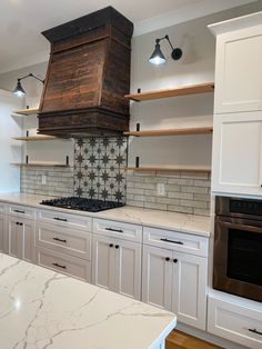 a stove top oven sitting inside of a kitchen next to white cupboards and counters