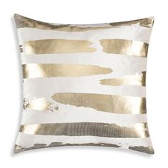 a gold and white pillow with metallic foil stripes on it's side, in front of a white background