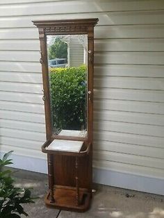 an old wooden mirror sitting on the side of a building next to a planter