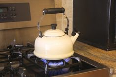 a white tea kettle sitting on top of a stove