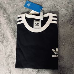 Brand: Adidas Originals Size: Medium (Measurements Pictured) Color: Black & White Material: 100% Cotton Condition: Great, Never Worn, New With Tags. Flaws: None Casual Black T-shirt With Three Stripes, Black Cotton T-shirt With Three Stripes, Black Cotton Top With Three Stripes, Black Cotton Tops With Three Stripes, Black Tops With Adidas Branding For Streetwear, Black T-shirt With Three Stripes, Black Three Stripes Crew Neck T-shirt, Black Crew Neck T-shirt With Three Stripes, Black Tops With Three Stripes Branding For Streetwear