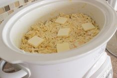 a white crock pot filled with rice and cubed cheese on the top side