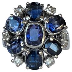 This classic cluster ring holds sapphires and diamonds around the edges. The sapphire is blue in colour. The sapphire total is 2.3 carat and the diamonds total 30pts. Ring Size: L 1/2 or 6 Cluster Dimensions: 17x17.5mm Weight: 6.3g Vintage Cluster Ring, Retro Ring, Diamond Gold, Diamond Cluster Ring, 3 Carat, Burmese, Diamond Cluster, Sapphire Diamond, Cluster Ring