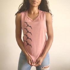 "Lele ka 'iwa mālie kai koʻo. \"When the ʻiwa bird flies (out to sea) the rough sea will be calm.\" Source: ʻŌlelo Noʻeau by Mary Kawena Pukui This comfortable muscle tank is soft and flowy with low cut armholes for a relaxed look. Get your sweat on with a good hula /ori tahiti workout. * 65% polyester/35% viscose* * Low cut armholes * Curved bottom hem * Side seams *Athletic Heather is 52% polyester/48% viscose; Black Heather is 80% rayon/20% polyester." Summer Cotton Tops With Bird Print, Sleeveless Graphic Print Top For Beach Season, Tropical Cotton Sleeveless Top, Tropical Sleeveless Cotton Top, Casual Summer Tops With Bird Print, Casual Bird Print Tops For Summer, Summer Cotton Tops With Flamingo Print, Summer Cotton Top With Flamingo Print, Cotton Top With Flamingo Print For Summer