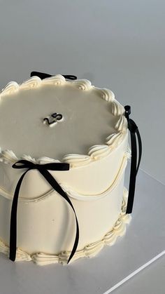 a large white cake with black ribbon on top