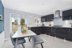 a kitchen with black cabinets and white counter tops, blue walls and gray stools