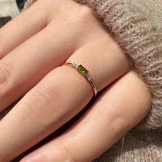 a woman's hand with a ring on it and a green stone in the middle