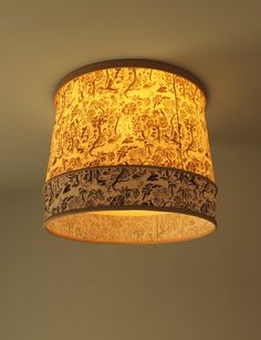 a lamp hanging from the ceiling with an intricate design on it's fabric shade