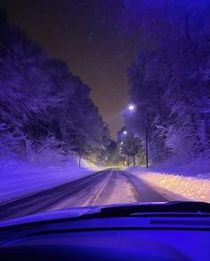 a car driving down a snow covered road at night