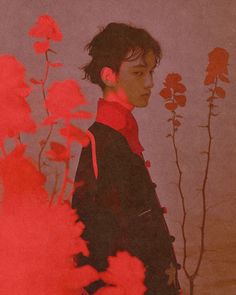 a young man standing in front of red flowers