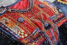 It is a beautiful Afghani dress with a beautiful greyish blue color and bright red threadwork. The contrast of red and blue colors make this dress an elegant piece of craft. It is embellished with beads, silver threadwork and coins. The fabric is of very good quality. It is light, trendy and sparkling. Bohemian Embroidered Celebration Dress, Bohemian Embroidered Dress For Celebration, Bohemian Dress For Festivals And Celebrations, Red Bohemian Ceremonial Dress, Red Bohemian Dress For Ceremonial Occasions, Red Bohemian Dress With Motifs, Red Mirror Work Dress For Festivals, Red Embellished Dress For Navratri, Red Embellished Festival Dresses