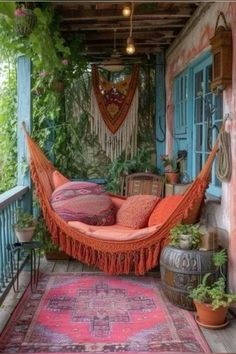 an orange hammock hanging from the side of a building with potted plants