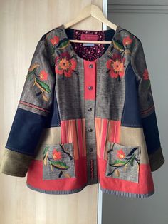 a jacket with flowers and birds on it hanging from a hanger in front of a door