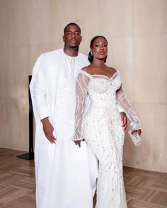 two people standing next to each other in white outfits and one is wearing an off the shoulder dress