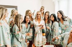 a group of women standing next to each other in matching robes and holding champagne bottles