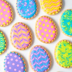 decorated cookies are arranged in the shape of easter eggs on a white surface with polka dots